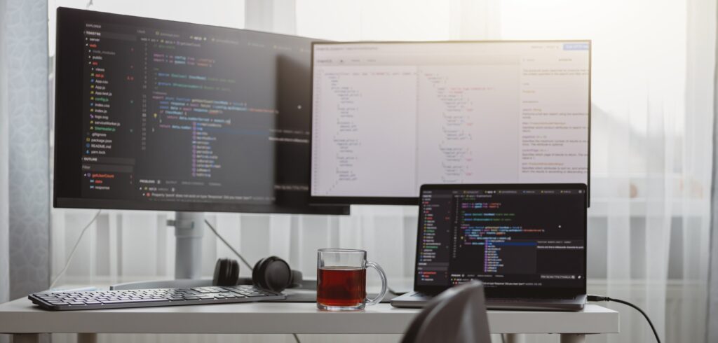 Interior shot. Workplace of a programmer, IT job, home, Computer monitors and laptop on desk