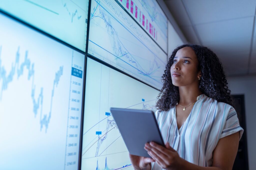 UK, York, Businesswoman with tablet looking at charts on interactive screens